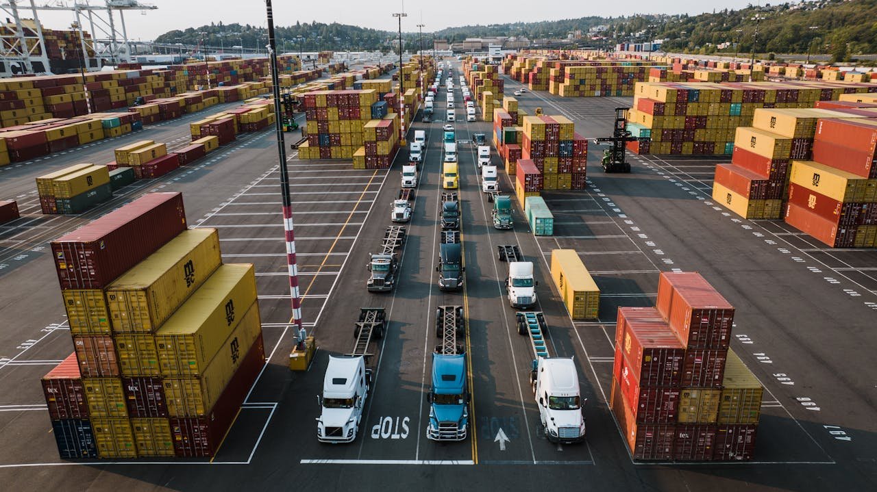 A bustling aerial shot of Seattle's shipping port with trucks lined up amongst colorful cargo containers.