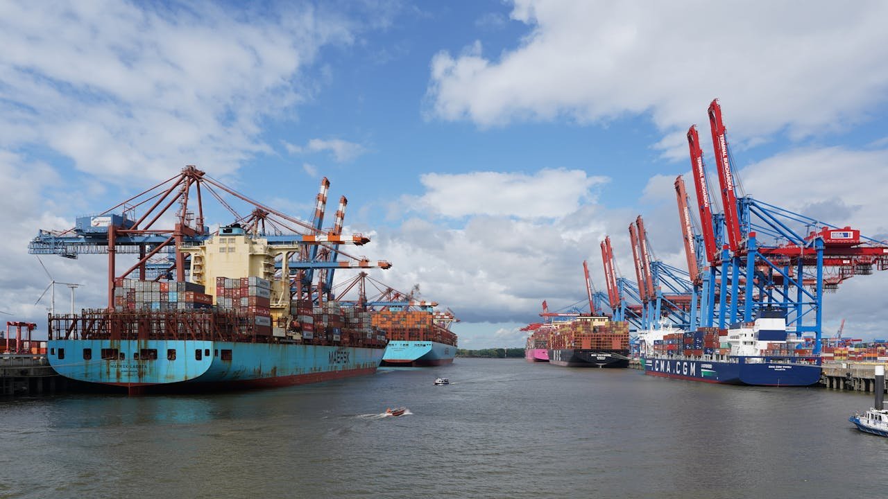 A vibrant view of container ships at Hamburg Port under a blue sky.